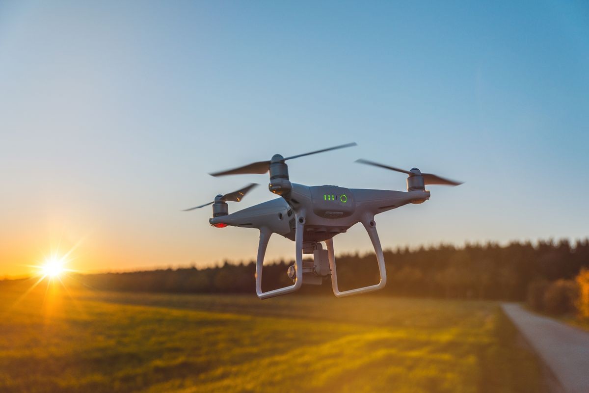 Photo of a flying white professional quadcopter drone camera during sunset 